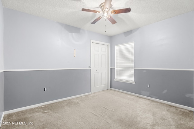 carpeted spare room featuring ceiling fan and a textured ceiling