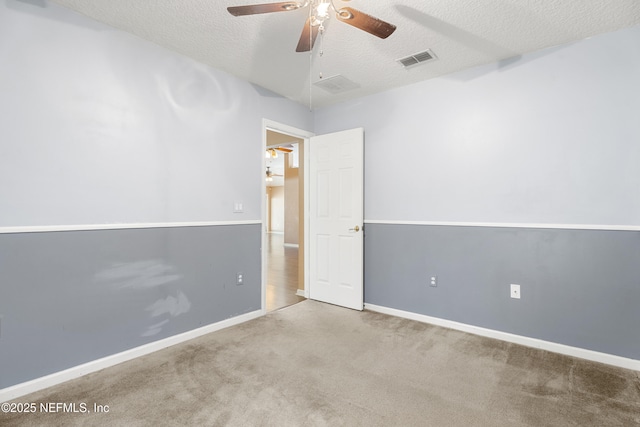 empty room featuring ceiling fan, a textured ceiling, and carpet flooring