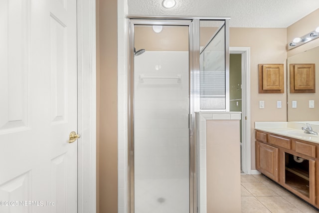 bathroom featuring tile patterned flooring, vanity, a shower with shower door, and a textured ceiling