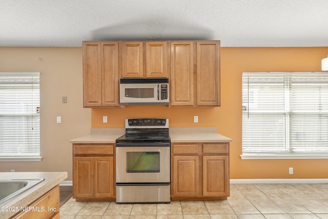 kitchen featuring light tile patterned floors, stainless steel appliances, sink, and a textured ceiling