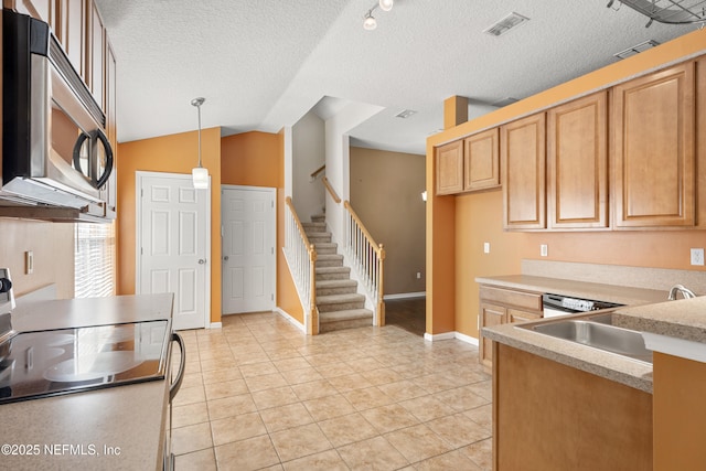 kitchen featuring vaulted ceiling, appliances with stainless steel finishes, hanging light fixtures, light tile patterned floors, and a textured ceiling