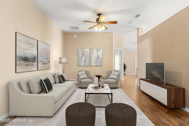 living room with wood-type flooring, a textured ceiling, and ceiling fan