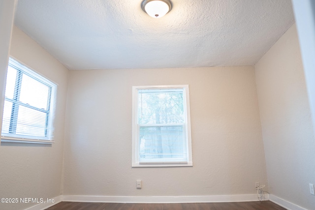 unfurnished room featuring a wealth of natural light and dark hardwood / wood-style flooring