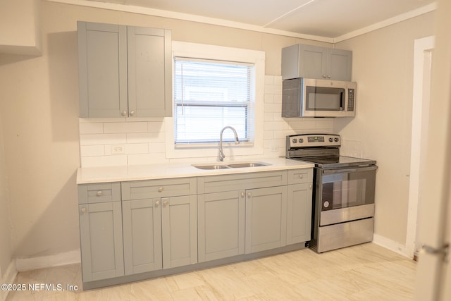 kitchen with tasteful backsplash, sink, gray cabinetry, and appliances with stainless steel finishes