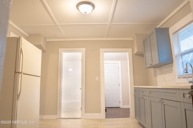 kitchen with gray cabinets, white fridge, and light hardwood / wood-style flooring