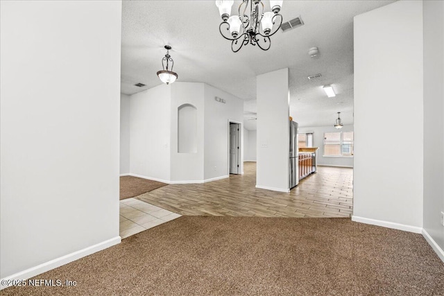 unfurnished living room with a notable chandelier, a textured ceiling, and carpet