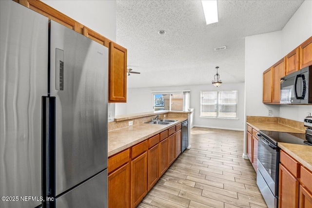 kitchen with sink, appliances with stainless steel finishes, a textured ceiling, decorative light fixtures, and kitchen peninsula