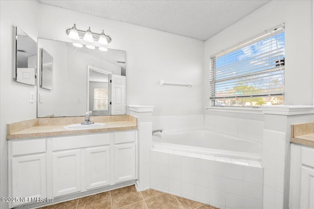 bathroom featuring vanity, tiled bath, tile patterned flooring, and a textured ceiling