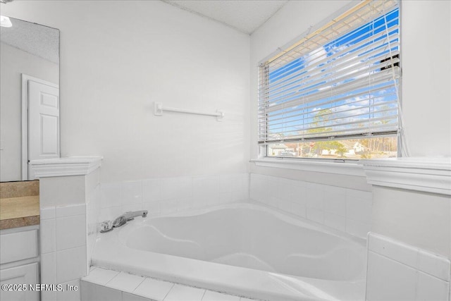 bathroom with vanity, a relaxing tiled tub, and a textured ceiling