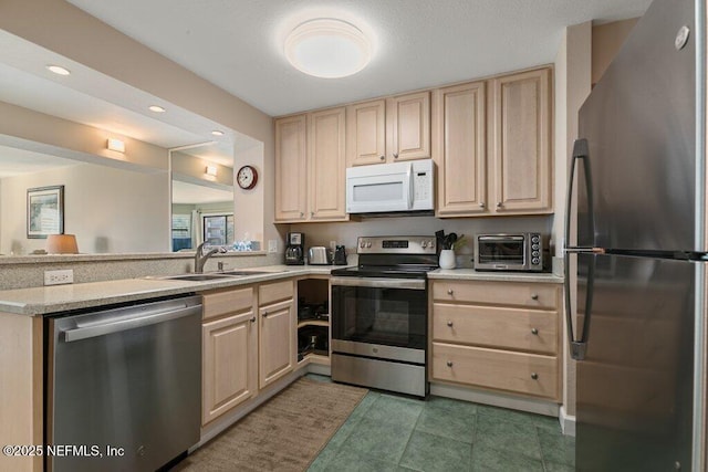 kitchen with stainless steel appliances, sink, light brown cabinetry, and kitchen peninsula