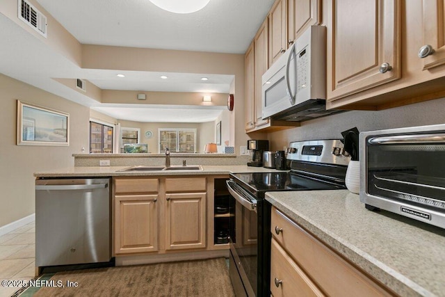 kitchen featuring sink, light tile patterned floors, light brown cabinets, and appliances with stainless steel finishes