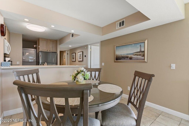 dining room featuring stacked washer and dryer and light tile patterned floors