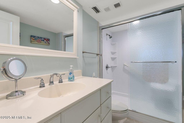 bathroom with toilet, vanity, and a shower with shower door