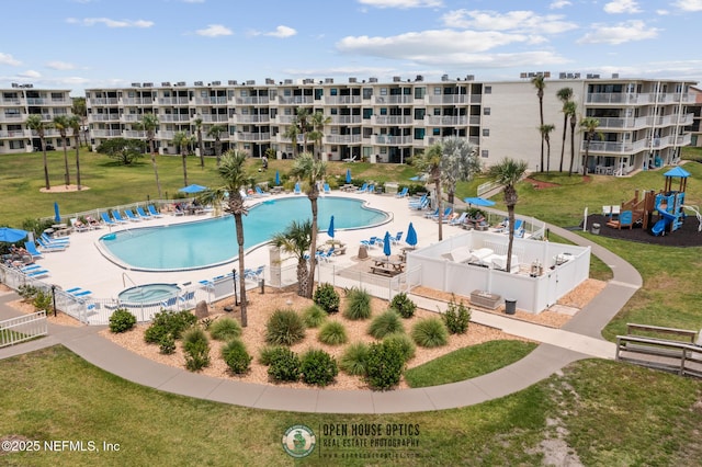 view of swimming pool featuring a playground, a patio, and a yard