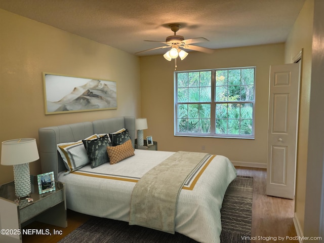 bedroom featuring ceiling fan, hardwood / wood-style floors, and a textured ceiling