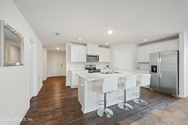 kitchen with stainless steel appliances, white cabinetry, sink, and an island with sink