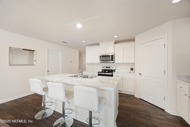 kitchen featuring appliances with stainless steel finishes, sink, a kitchen island with sink, and white cabinets