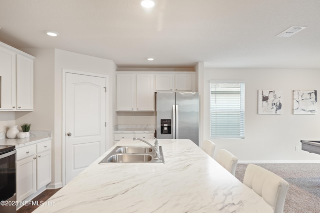 kitchen with sink, white cabinets, a kitchen bar, dark carpet, and stainless steel appliances