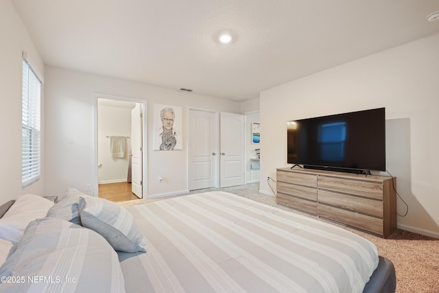 bedroom featuring connected bathroom and light carpet