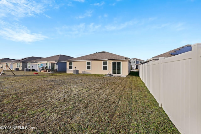 rear view of house featuring cooling unit and a yard