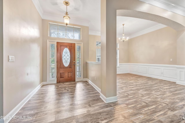 entryway with wood finished floors and crown molding