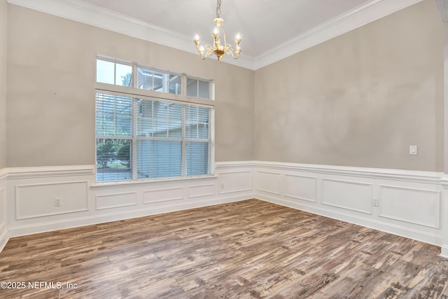 unfurnished room with a wainscoted wall, ornamental molding, a notable chandelier, and wood finished floors