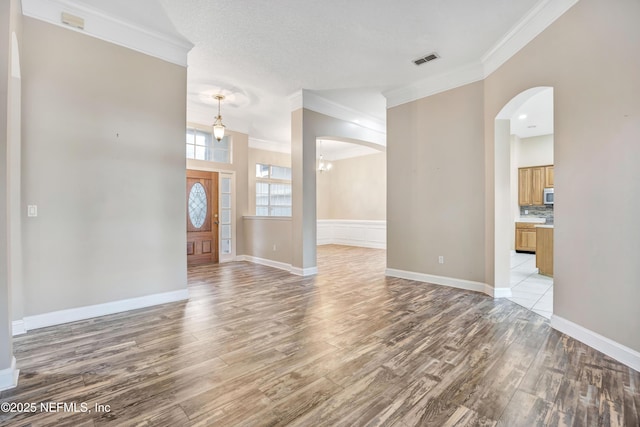 entryway with visible vents, crown molding, and light wood-style flooring