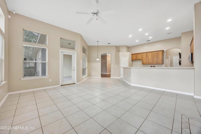 unfurnished living room featuring arched walkways, ceiling fan, light tile patterned flooring, recessed lighting, and baseboards