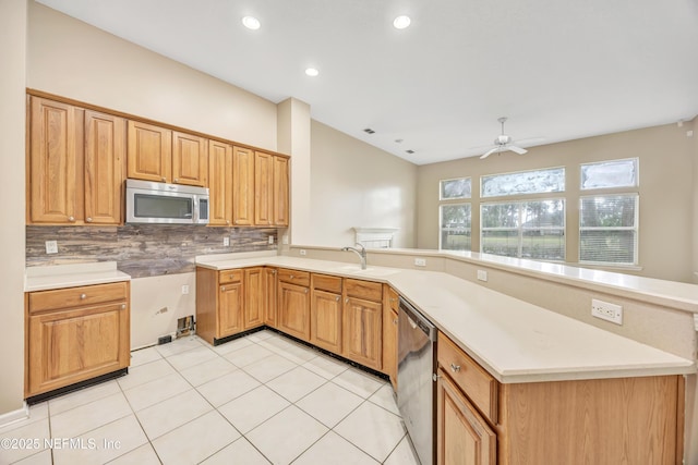 kitchen featuring decorative backsplash, a peninsula, stainless steel appliances, light countertops, and a sink