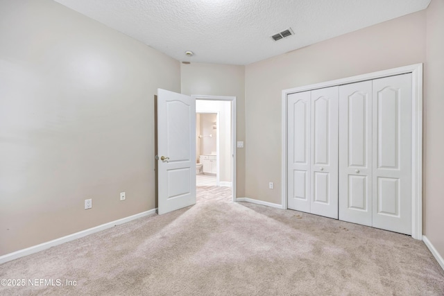 unfurnished bedroom with light carpet, baseboards, visible vents, a textured ceiling, and a closet