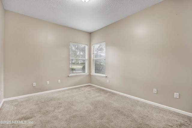 carpeted spare room featuring a textured ceiling and baseboards