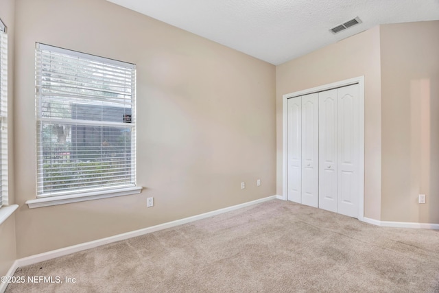 unfurnished bedroom featuring a closet, visible vents, light carpet, and baseboards