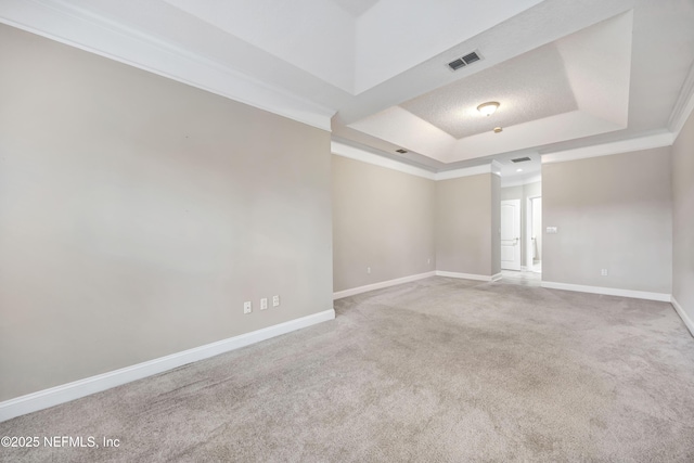 spare room with visible vents, baseboards, a raised ceiling, ornamental molding, and carpet