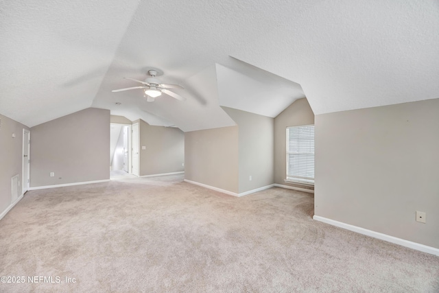 bonus room featuring a textured ceiling, baseboards, lofted ceiling, and light colored carpet