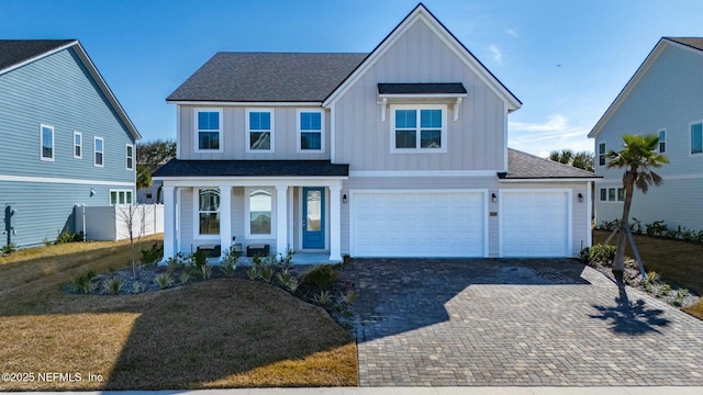 view of front of property featuring a garage, covered porch, and a front lawn