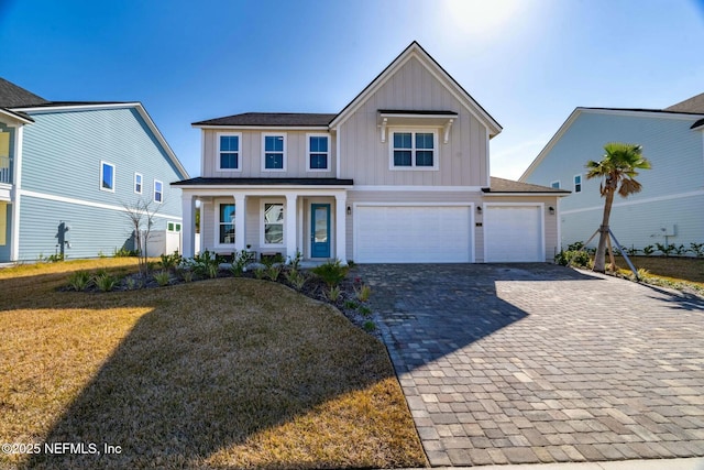 view of front of property featuring a garage, a front yard, and covered porch