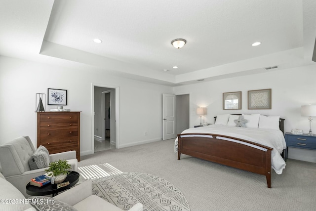 bedroom with a raised ceiling and light carpet