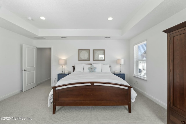 carpeted bedroom with a raised ceiling