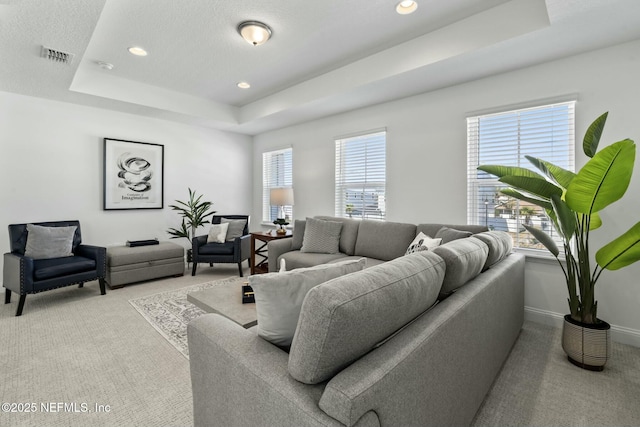 living room with light colored carpet, a textured ceiling, and a tray ceiling