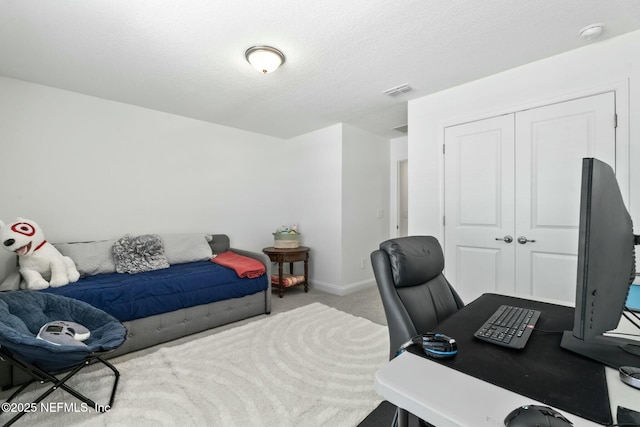 carpeted bedroom with a textured ceiling and a closet