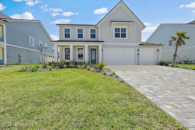 view of front of house featuring board and batten siding, decorative driveway, a front yard, an attached garage, and a garage