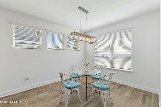 dining area with light wood-style flooring, a notable chandelier, and baseboards
