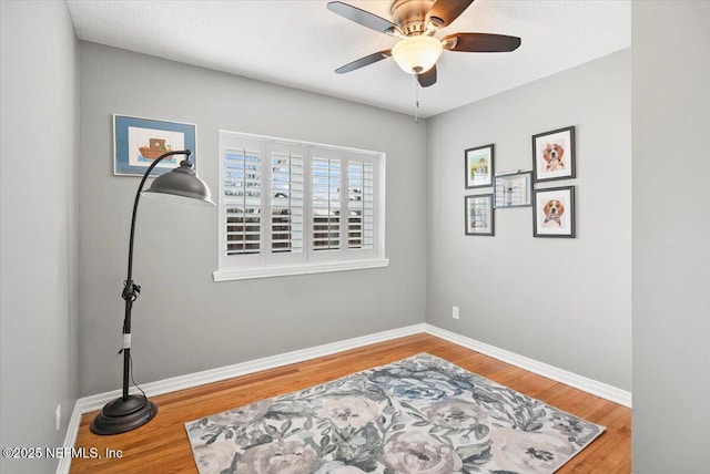 living area featuring wood-type flooring and ceiling fan