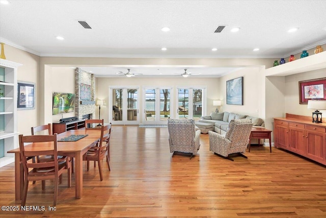 living room with a large fireplace, ornamental molding, light hardwood / wood-style floors, and a textured ceiling