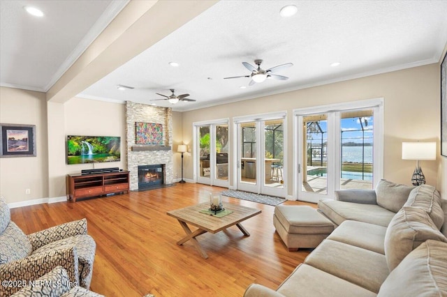 living room featuring a stone fireplace, crown molding, a textured ceiling, hardwood / wood-style flooring, and ceiling fan