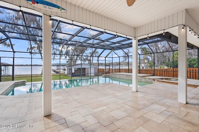 view of swimming pool with a water view, a patio, and glass enclosure