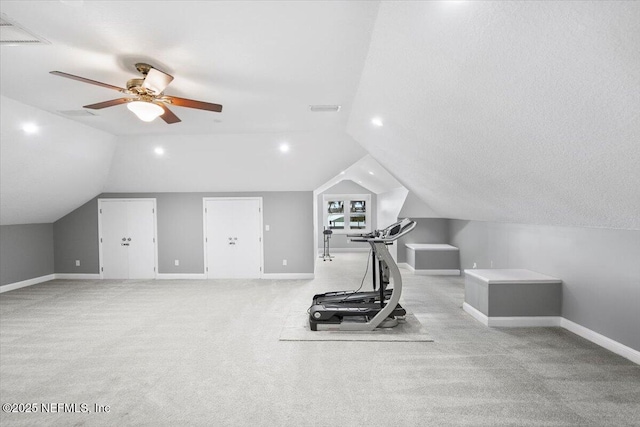 exercise room featuring light carpet, a textured ceiling, vaulted ceiling, and ceiling fan