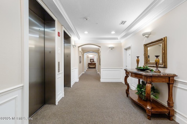 corridor with crown molding, elevator, and light colored carpet