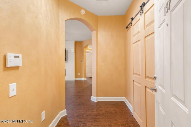 hall featuring dark wood-type flooring and a barn door