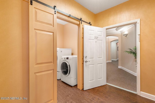 laundry room featuring washer / dryer, a barn door, and hardwood / wood-style floors